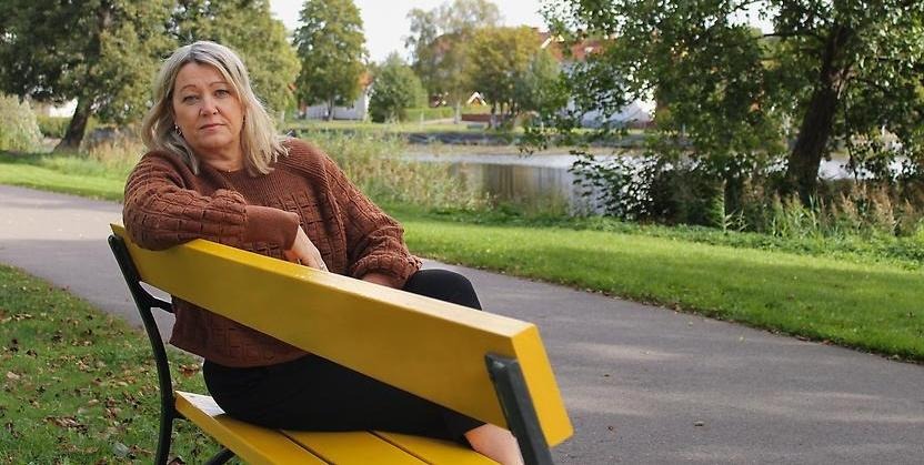 Kvinna sitter på en gul bänk