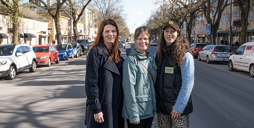 Tre kvinnor vid Storgatan, bland bilar och butiker.