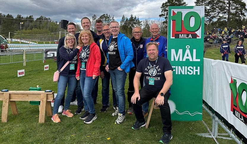 En grupp personer poserar vid tiomila-skylt