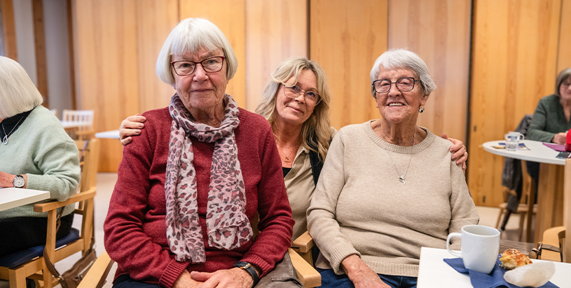 Tre personer med en trävägg i bakgrunden.