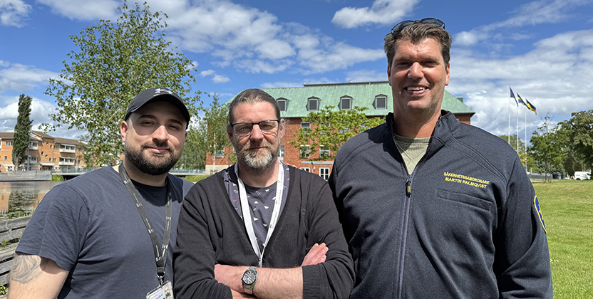 Tre personer poserar med stadshuset i bakgrunden.