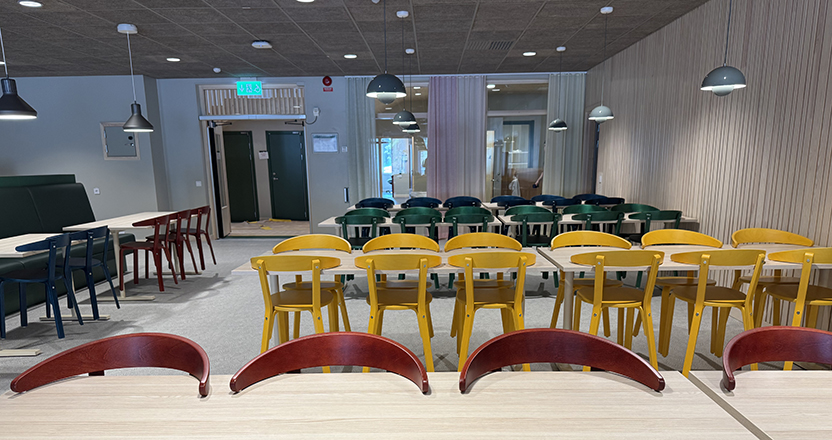 Sal med matbord och färgglada stolar.