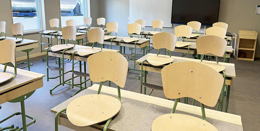 Klassrum med bänkar och stolar, tavla och tv.