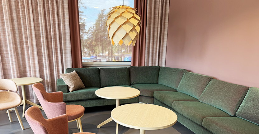 Rum i mjuka gröna och rosa färger med soffa och fåtöljer.